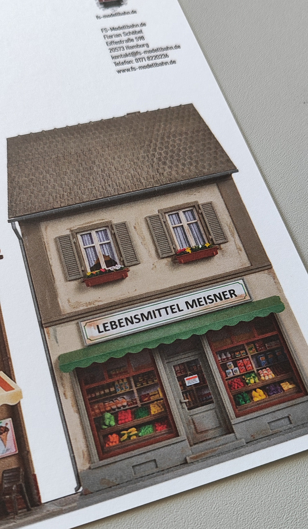 Modellbahnhintergrund zweigeschossige Gebäude Apotheke und Eiscafe Milano und Lebensmittelgeschäft und Baum H0 1zu87 KM00000086