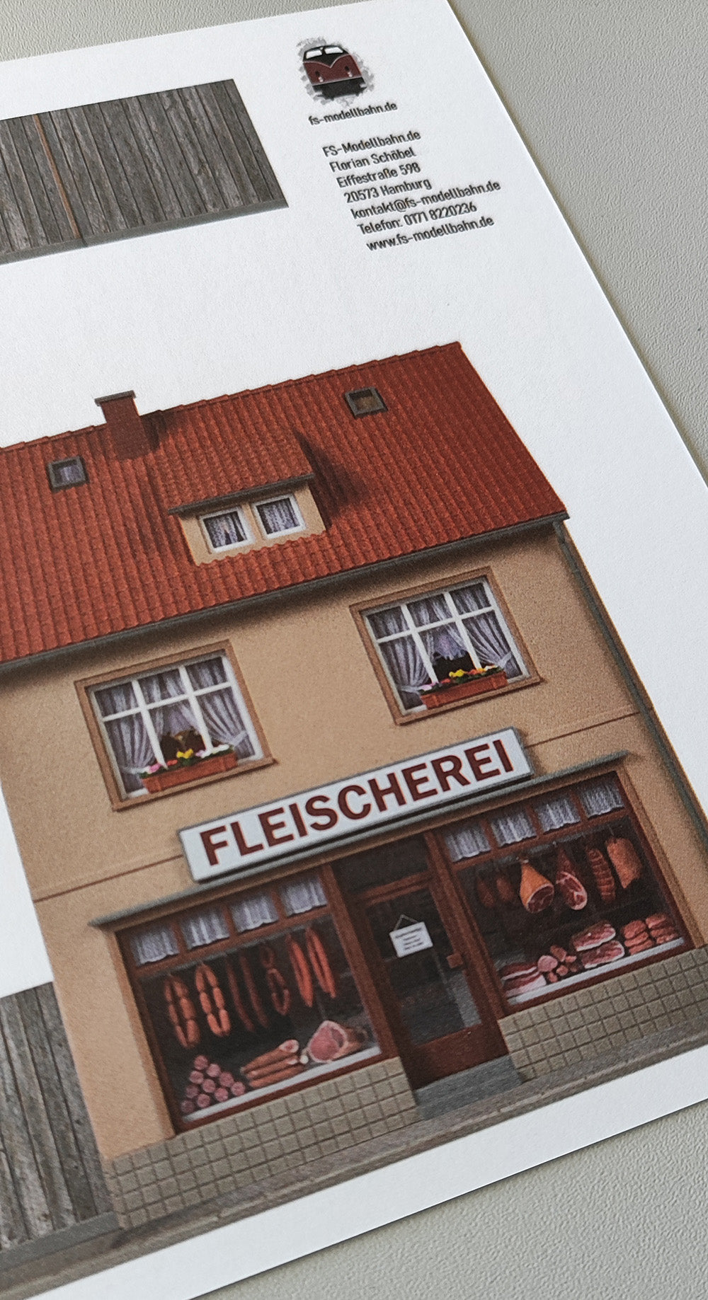 Modellbahnhintergrund zweigeschossige Fassaden mit Bäckerei Schmidt und Fleischerei mit Bretterzaun Spur H0 1zu87 KM00000088