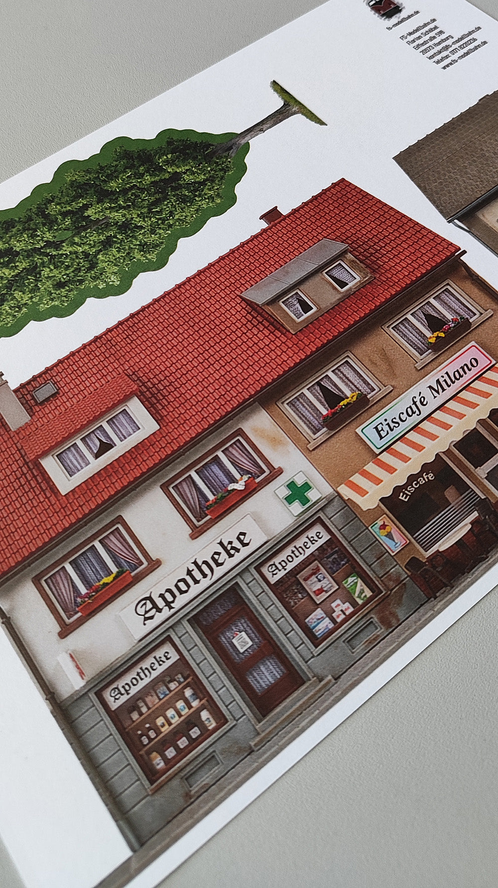 Modellbahnhintergrund zweigeschossige Gebäude Apotheke und Eiscafe Milano und Lebensmittelgeschäft und Baum H0 1zu87 KM00000086